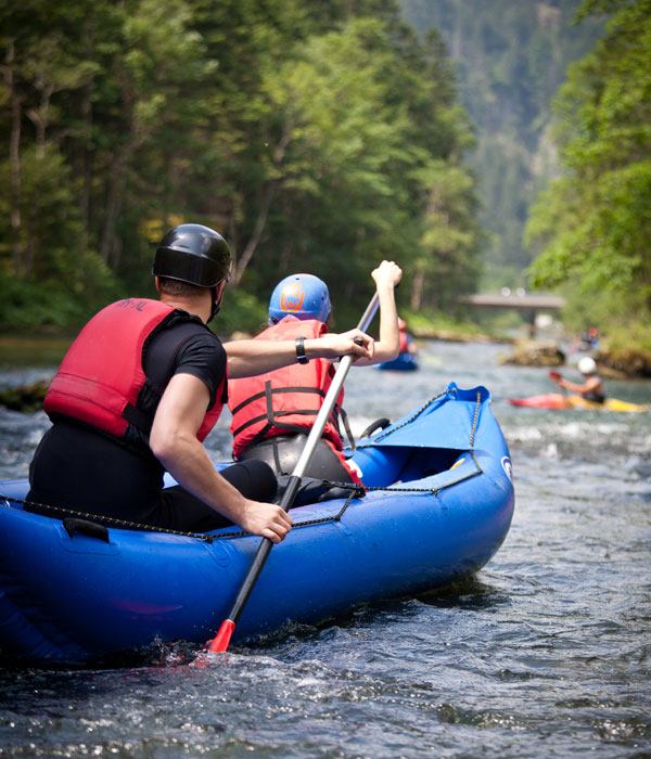People steering kayak down a river