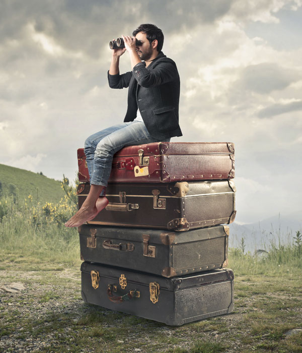 Man sitting on stack of suitcases