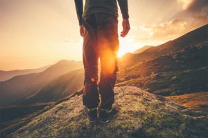 man standing on rock, mountain vista, sunset